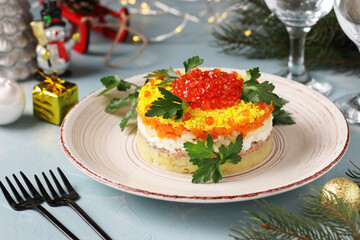 Festive salad Mimosa with canned fish, potatoes, cheese, carrots and eggs, garnished with red caviar and parsley leaves