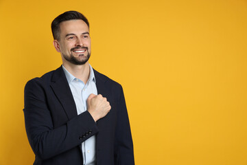 Man making promise on orange background, space for text. Oath gesture