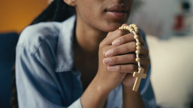 Close-up of a young female holding beads in her hands while saying a prayer