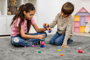 Children playing with balancing stones on floor indoors