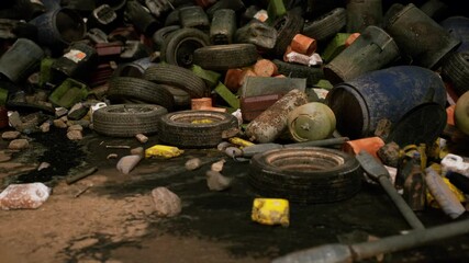 A cluttered urban dump reveals a large accumulation of worn tires, trash bins, and various debris scattered on the ground, highlighting significant waste management issues in the area.