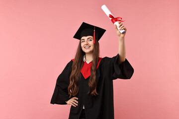 Happy student with diploma after graduation on pink background