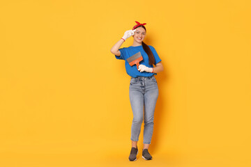 Young decorator with putty knife on orange background