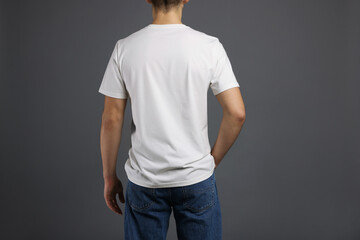 Obraz premium Man in stylish t-shirt on grey background, back view. Mockup for design