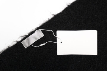 A black wool scarf with neatly attached blank white tags and a subtle empty inner label. The soft fabric texture and neutral tag appearance highlight the quality.