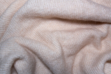 Beige wool fabric with waves: The surface of wool material in a beige shade forms gentle waves. The soft color and delicate texture of the natural beige wool create a cozy and relaxing atmosphere.