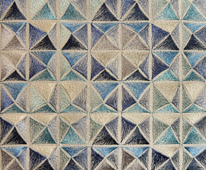 Close up of blue beveled geometrical pattern fabric, printed in many shades giving such a 3D effect in blue, grey, and white shades. Fabric seamless background texture