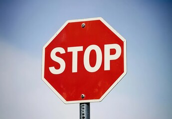 A red stop sign with the word "STOP" written in white on it, standing against a plain background.