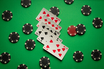 On a bright green table are poker cards with a full house or full boat combination and chips from winnings or bets are scattered chaotically