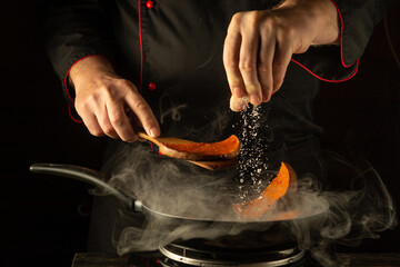 In a dimly lit kitchen, a chef expertly seasons pumpkin slices with salt, creating a fragrant...