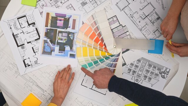 Group of architects, creative interior designers and team members meeting in boardroom at desk, discussing design project of new house, picking palette, top view.