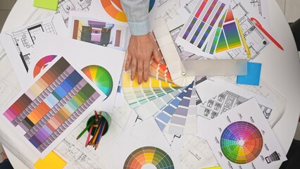 Group of architects, creative interior designers and team members meeting in boardroom at desk, discuss design project of new house, demonstrating palette, top view.