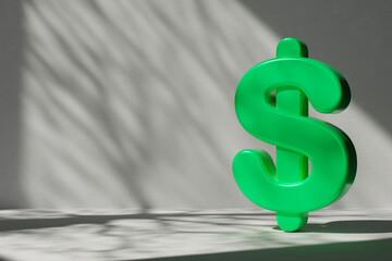 Vibrant green 3D dollar symbol against minimalist gray background with dramatic shadow patterns. Ideal for financial, economic, and eco-friendly business concepts, marketing, and advertising designs.