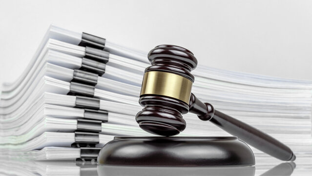 Judge's gavel and a stack of court files and documents on a desk. Judicial case backlogs and accumulation.