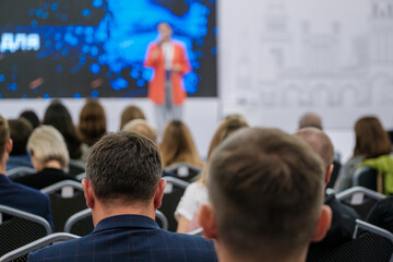 Obraz premium People attending a conference, focused on a presentation by speaker on stage. Audience engaged and seated in modern business event. Capturing professional environment collective gathering discussion
