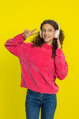Happy joyful Caucasian girl in glasses listening music on headphones and dancing disco fooling...
