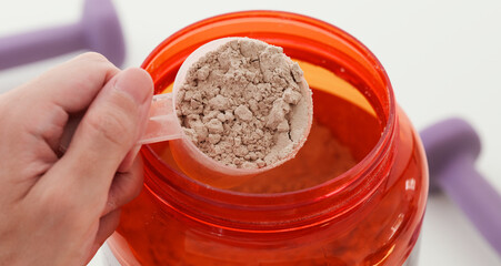 A man holding a scoop of soy protein isolate powder with chocolate in his hand. Close up.