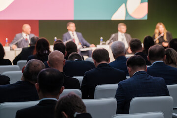 Business professionals gathered for formal panel discussion with focus on interaction and strategy.