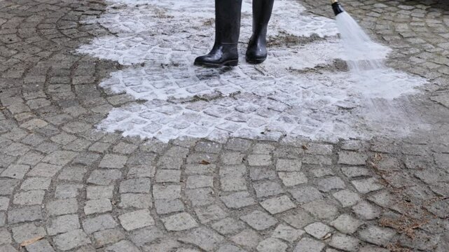 Worker cleaning stone pavement