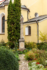 A stone pillar with a head on top of it is in front of a yellow building