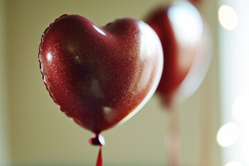 Two heart shaped mylar balloons against bokeh lights background, Valentine's Day concept