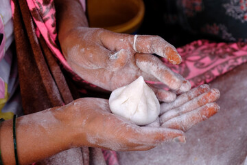 Woman making sweet rice modak stuffed with grated coconut and jaggery, Steamed or ukdiche Modak. It's a traditional sweet dish made out of coconut, jaggery