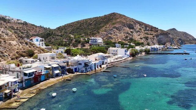 Aerial drone cinematic video of iconic and picturesque fishing village of Klima built by the shore with colourful traditional fishing boat houses called syrmata in island of Milos, Cyclades, Greece