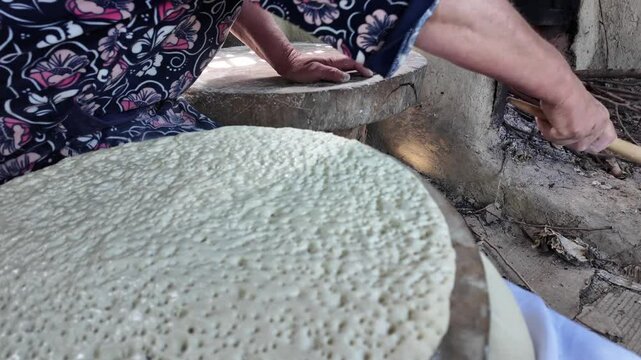 preparing bread in a traditional Dagestan village bakery. Bread is a flatbread baked in a Koryuk oven, common in the cuisine of the North Caucasus.