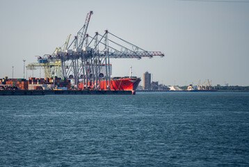 Fototapeta premium view of tall metal crane next to the water in summer against a clear sky on a sunny day