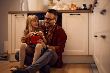 Curious little girl opening gift box with her father at home.