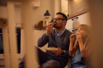 Carefree father and daughter enjoying in tasting sandwiches in kitchen.