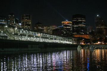 Obraz premium view of a parking lot in a city with tall buildings in the background next to a river at night with lights on