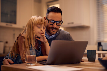 Little girl and her father using computer at home.