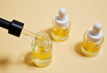 Dropper dispensing golden liquid from a small glass bottle.