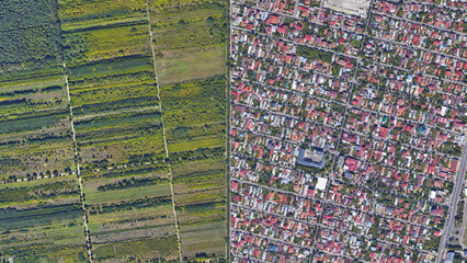 Fields and city border, the border separating colorful buildings and green fields, looking down...