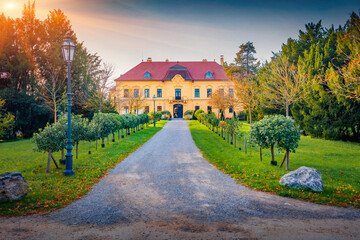 Naklejka premium Empty walkway to the ancient Eckartsa castle. Impressive autumn cityscape of Eckartsau village, in the district of Ganserndorf, Austria, Europe. Fantastic sunset in Austrian countryside.