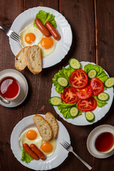 Tomorrow two plates of scrambled eggs with sausages and white bread, tomato salad and tea in cups