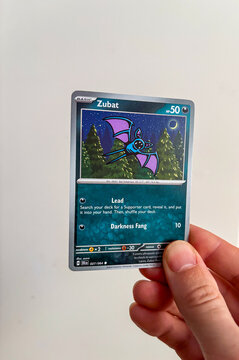 Hamburg, Germany - 12232024: male hand holding the English pokemon paper trading card called ZUBAT from the Shrouded Fable set. 