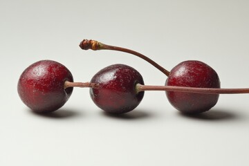 three cherries connected by stems on a white background
