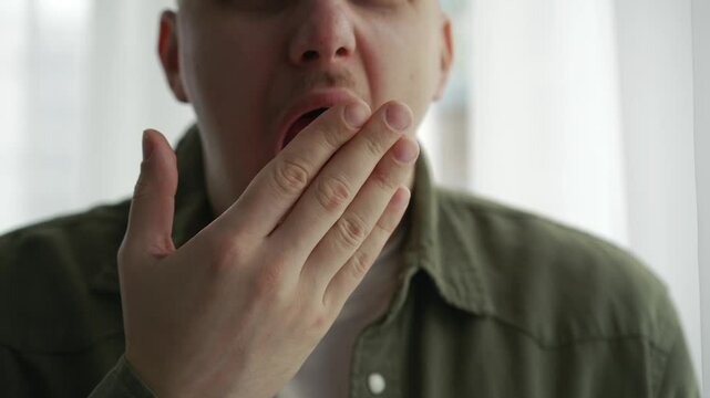 sleepy young man yawns from overwork.
The man in the green shirt yawns.
A person wants to sleep and cannot stop yawning.
Yawning, man, sleep, fatigue, overwork