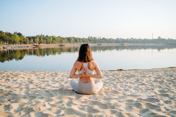 A tranquil and serene scene of a woman gracefully practicing yoga by the sparkling waters edge in...