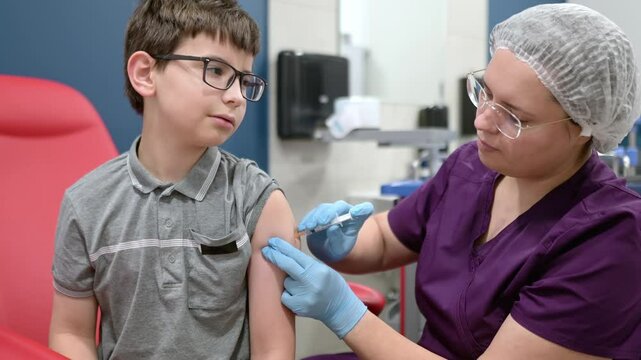 A boy is being vaccinated. A child is given a vaccine during an epidemic or outbreak of a disease. A kid during routine vaccination