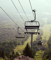 view of a chairlift mid air on a mountain on a foggy day of summer