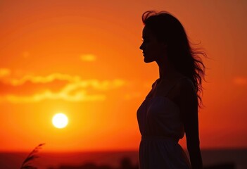 Silhouette of a woman standing against a fiery sunset