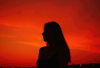 Silhouette of a woman against a vibrant red sunset.