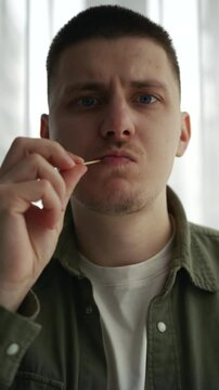 A man uses a toothpick.
A man with a toothpick in his teeth.
The food is stuck in the teeth and the man takes the food out of his teeth.
Dental floss.
Dental care.