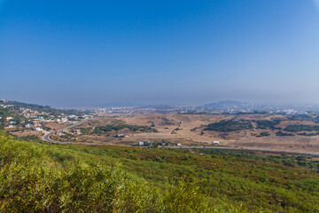 breathtaking panoramic view of a coastal landscape, with rolling hills, a sprawling town, and a pristine coastline stretching towards the horizon, offering a serene and picturesque scene