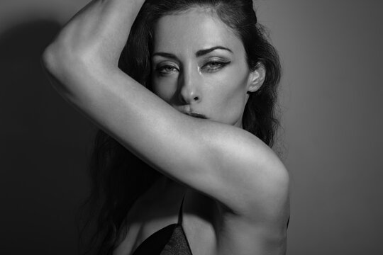 Sexy bright makeup and red lipstick elegant woman in party black top posing in studio bright spot light and shadow, low key lighting with empty copy space. Closeup