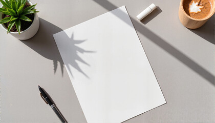 A4 paper mockup on gray desk with plant, pen, and clay pot in natural light and copy space