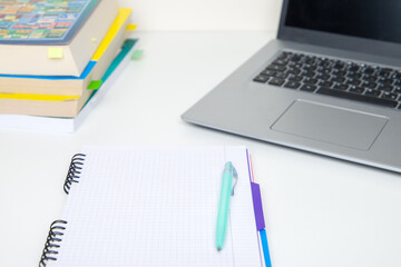 Laptop and notepad with pen on white table. Top view